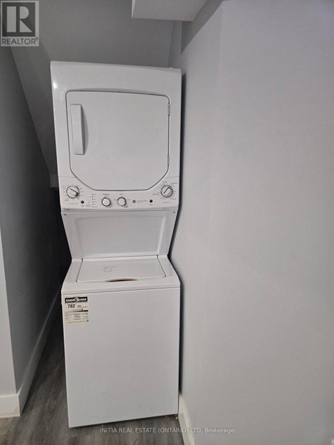 A white dryer is in a small room with a grey wall.