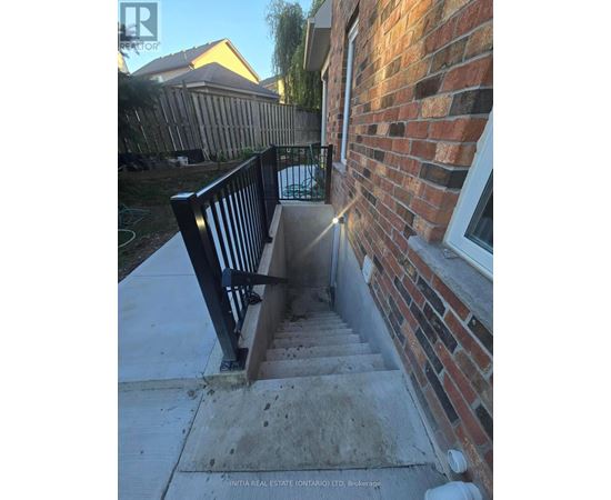 A set of stairs leading up to a brick building with a black railing.