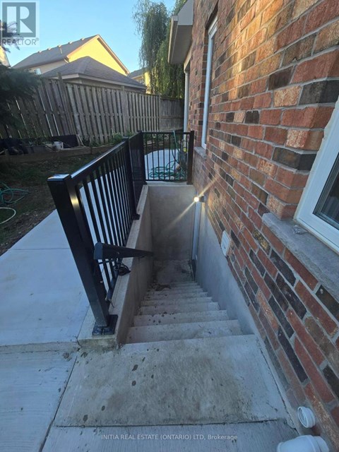 A set of stairs leading up to a brick building with a black railing.