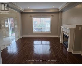 A spacious living room with wood flooring and a fireplace.