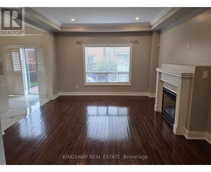 A spacious living room with wood flooring and a fireplace.