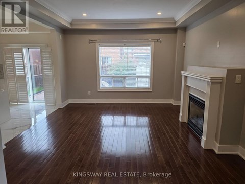 A spacious living room with wood flooring and a fireplace.
