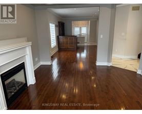 A Kingsway Real Estate Brokerage sign is displayed in a spacious room with hardwood floors and a fireplace.