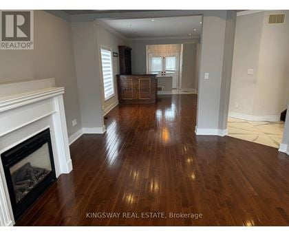 A Kingsway Real Estate Brokerage sign is displayed in a spacious room with hardwood floors and a fireplace.