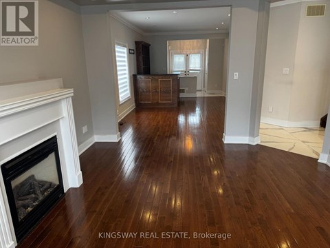 A Kingsway Real Estate Brokerage sign is displayed in a spacious room with hardwood floors and a fireplace.
