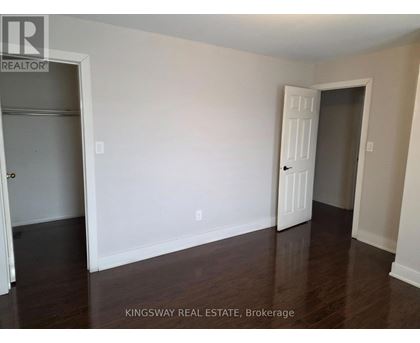 A room with a white door and a white wall with a Kingsway Real Estate sign.