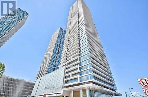 A tall building with a glass facade stands next to a smaller building with a mesh facade.