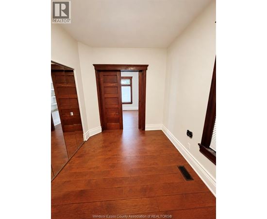 A hallway with wood floors and white walls.