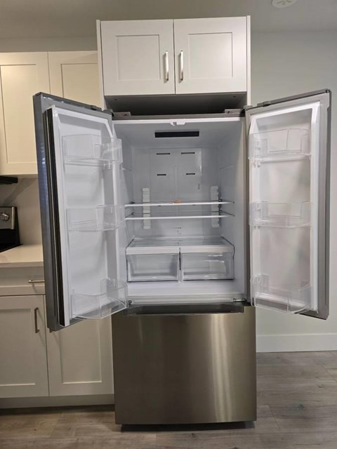A stainless steel refrigerator with its door open in a kitchen.