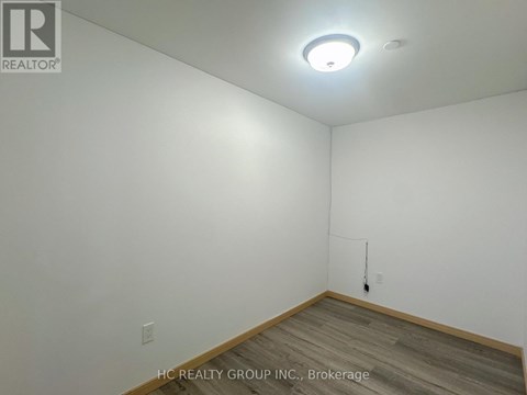 A room with a white wall and a wooden floor.