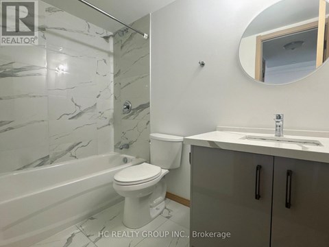 A bathroom with a marble tile shower, toilet, and sink.