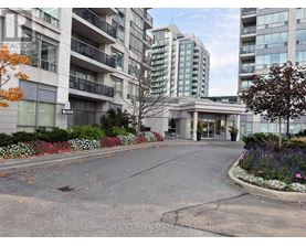A street view of a residential area with apartment buildings and a realtor sign.