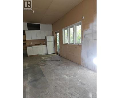 A room with a white fridge and cabinets in a house under construction.