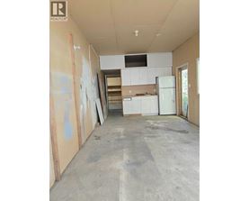 A room under construction with a white fridge and cabinets.