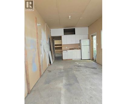 A room under construction with a white fridge and cabinets.