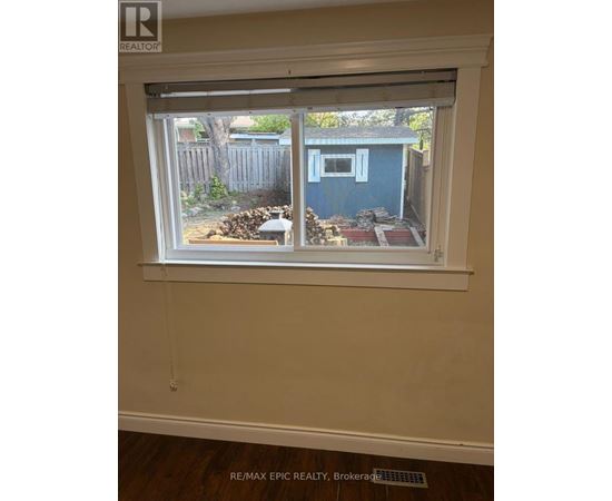A window with a view of a blue shed and a wooden fence.