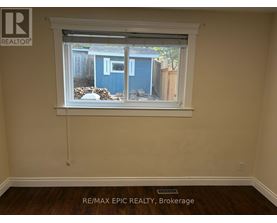 A room with a window showing a blue shed outside.