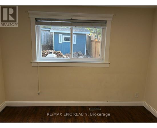 A room with a window showing a blue shed outside.