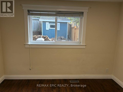 A room with a window showing a blue shed outside.