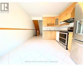 A kitchen with white tiled floors and wooden cabinets.
