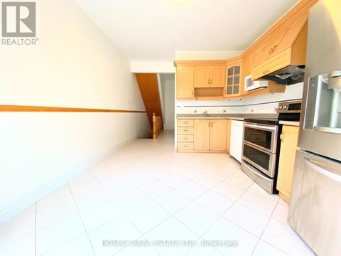A kitchen with white tiled floors and wooden cabinets.
