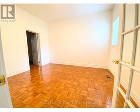 A room with wooden flooring and a doorway leading to another room.