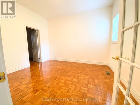 A room with wooden flooring and a doorway leading to another room.