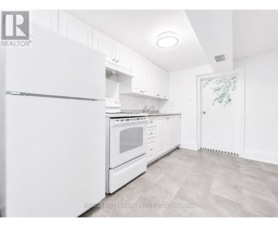 A white kitchen with a refrigerator, oven, and cabinets.