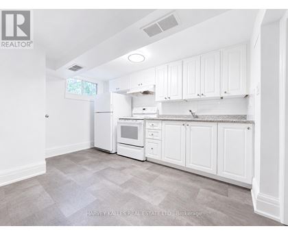 A kitchen with white cabinets and appliances in a real estate listing.
