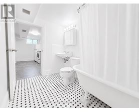 A white bathroom with a black and white floor.