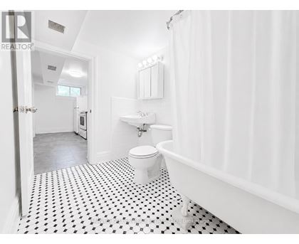 A white bathroom with a black and white floor.