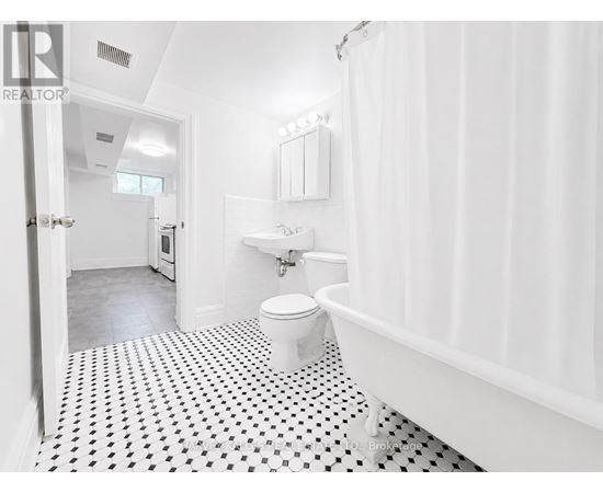 A white bathroom with a black and white floor.