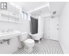 A white toilet sits in a bathroom with a black and white floor.