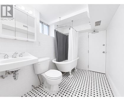 A white toilet sits in a bathroom with a black and white floor.