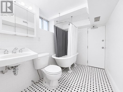A white toilet sits in a bathroom with a black and white floor.