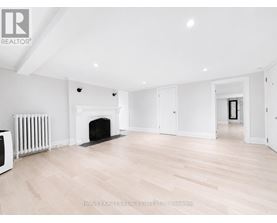 A spacious room with a fireplace and wooden flooring.