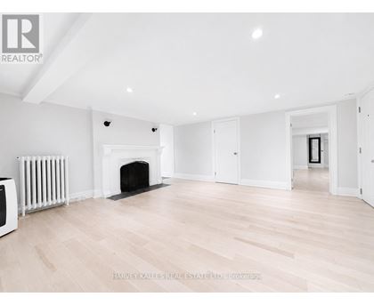 A spacious room with a fireplace and wooden flooring.