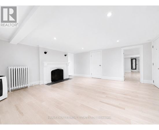 A spacious room with a fireplace and wooden flooring.