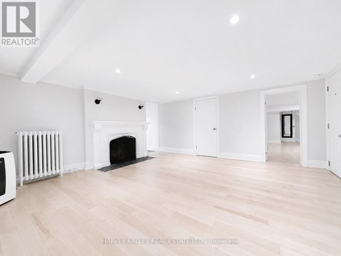 A spacious room with a fireplace and wooden flooring.