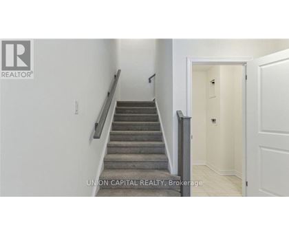 A staircase in a hallway with a brokerage sign.