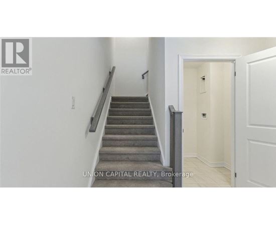 A staircase in a hallway with a brokerage sign.