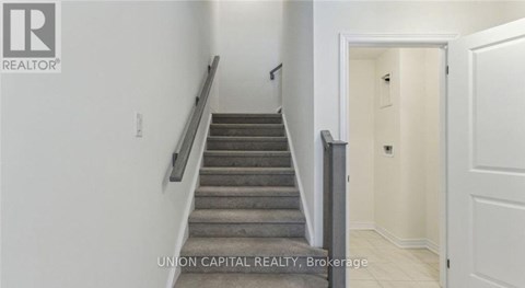 A staircase in a hallway with a brokerage sign.