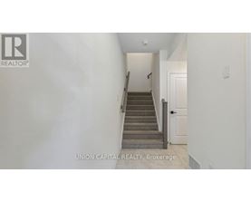 A hallway with a staircase leading to a door.