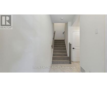 A hallway with a staircase leading to a door.