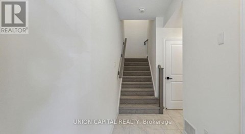 A hallway with a staircase leading to a door.