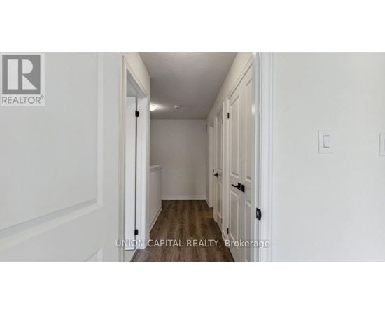 A hallway with white walls and wooden floors.