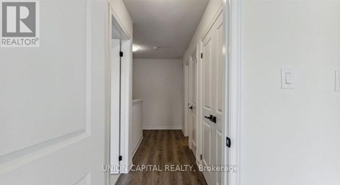 A hallway with white walls and wooden floors.