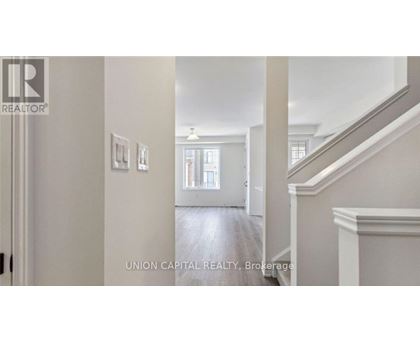 A hallway with a staircase and a door leading to a bathroom.