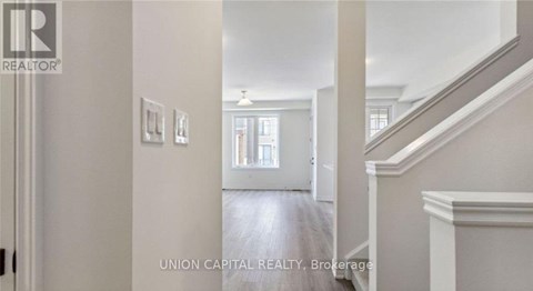 A hallway with a staircase and a door leading to a bathroom.