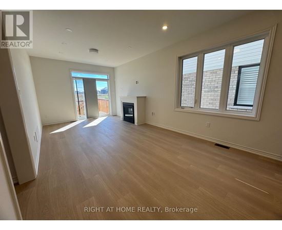 A spacious room with wooden flooring and a large window.